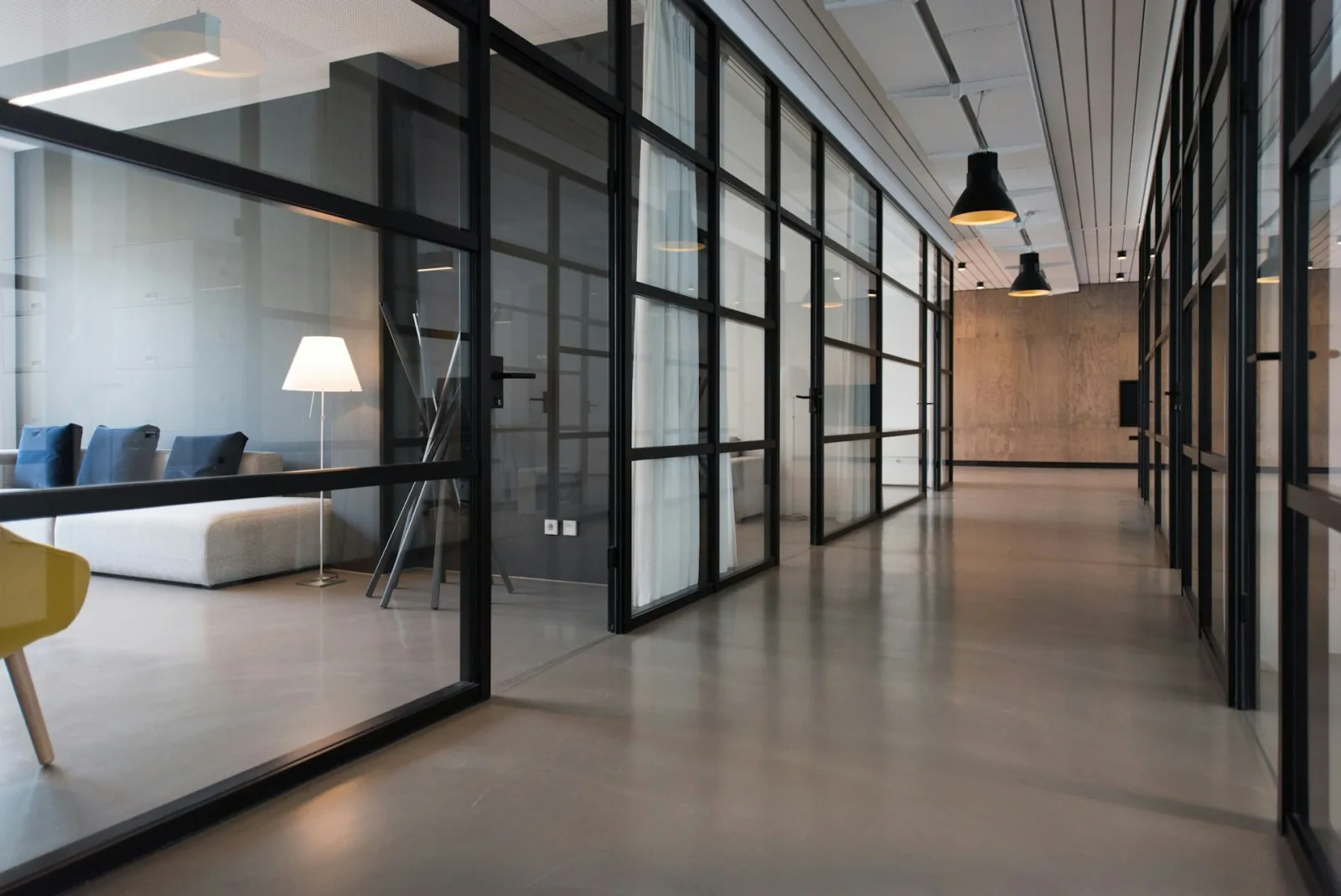 Modern glass-walled office corridor and meeting rooms