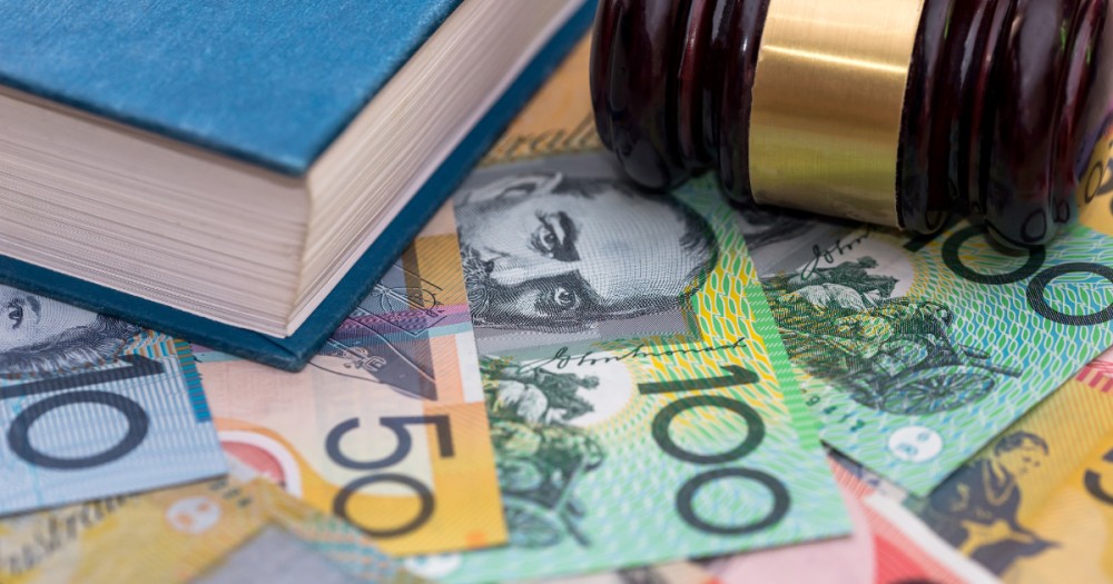 A judge's gavel resting on Australian banknotes beside a law book
