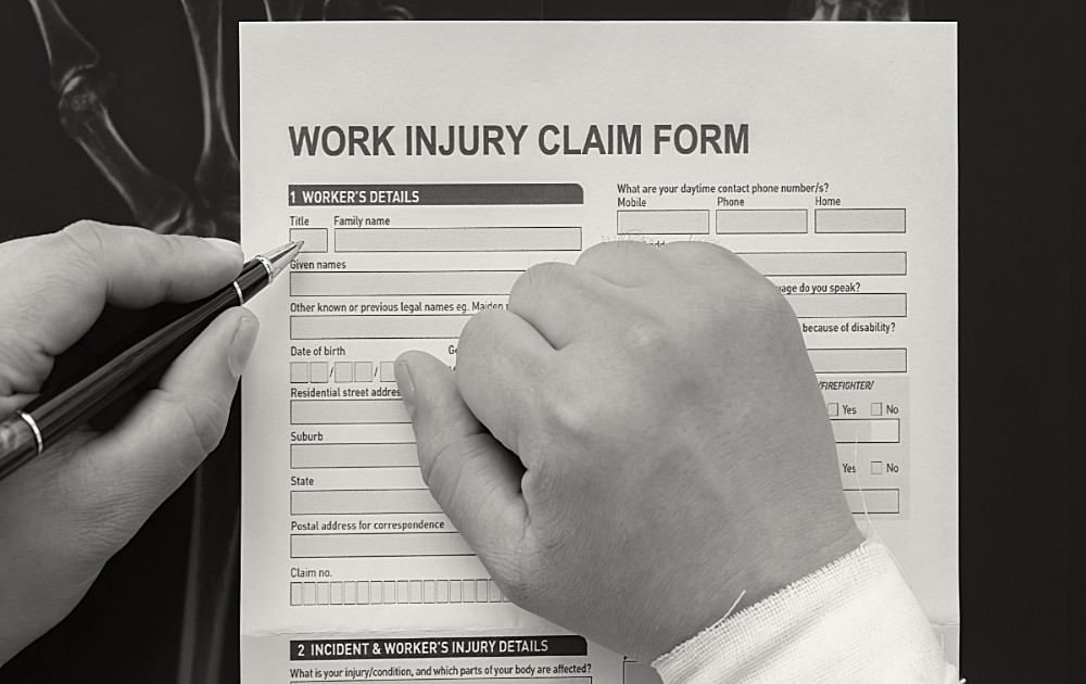 A person with a bandaged wrist completing a work injury claim form