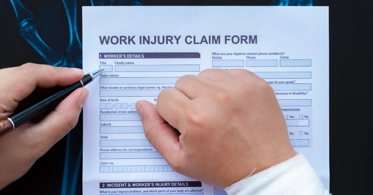 Person with a bandaged wrist completing a work injury claim form